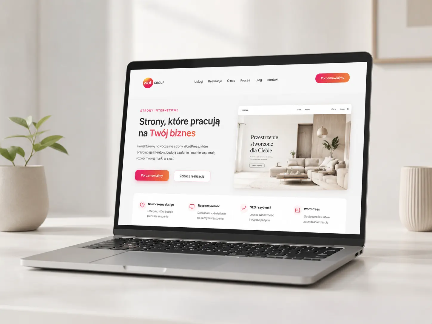 Strona internetowa WOH GROUP wyświetlona na laptopie w jasnym, nowoczesnym wnętrzu